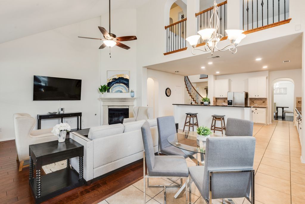 A spacious living area with a sofa, chairs, a TV, a fireplace, and a kitchen in the background.