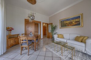 Ein Essbereich mit Holztisch und Stühlen, einem weißen Sofa, einem Glastisch und einem Bild an der Wand.