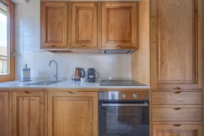 Eine Küche mit Holzausstattung, einer Edelstahl-Spüle, einer Kaffeemaschine und einem Backofen.