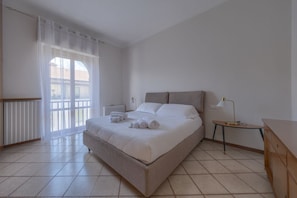 Ein Schlafzimmer mit einem Bett, einem Nachttisch, einer Lampe und einem Fenster mit Vorhängen.