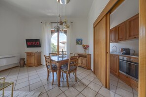Eine Küche mit Holzschränken, einem Esstisch mit Stühlen, einer Hängeleuchte und einem Schild mit dem Schriftzug 'NETFLIX'.
