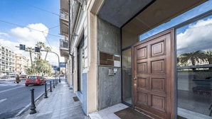A hotel entrance with a large wooden door, a glass entrance, and a sidewalk with bollards. - [Stunning Residence] Marina & City view • A/C (Sanremo)