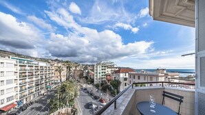 A balcony with a clear view of a coastal street, buildings, and a distant ship. - [Stunning Residence] Marina & City view • A/C (Sanremo)