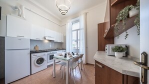 A modern kitchen with white cabinetry, a dining table with chairs, a washing machine, and a built-in oven. - [Stunning Residence] Marina & City view • A/C (Sanremo)