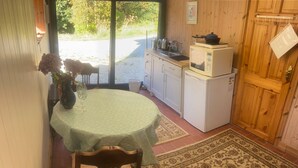 A compact kitchen with a microwave and stove, a dining table with a chair, and a patterned rug. - Sanctuary Apartment Nestled in Nature (Westport)