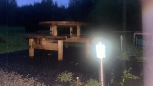 Una mesa de picnic de madera con banco, rodeada de un jardín.