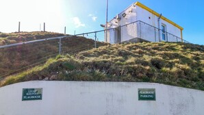 A concrete wall with two green signs, one reads 'LIGHT KEEPERS FLAGHOUSE' and the other 'FLAGHOUSE PARKING'. - Lightkeepers Flaghouse (Eyemouth)
