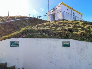 A concrete wall with two green signs, one reads 'LIGHT KEEPERS FLAGHOUSE' and the other 'FLAGHOUSE PARKING'. - Lightkeepers Flaghouse (Eyemouth)