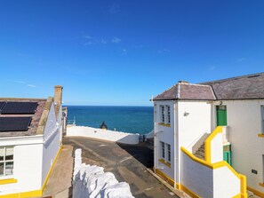 A coastal building with a white facade, yellow trim, and a staircase leading to a higher level. - Lightkeepers Flaghouse (Eyemouth)