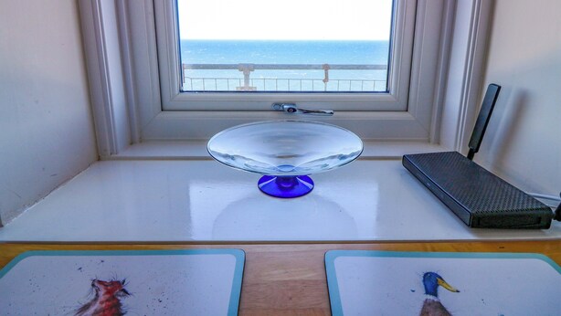 A room with a window, a glass cake stand, a router, and two mouse pads. - Lightkeepers Flaghouse (Eyemouth)