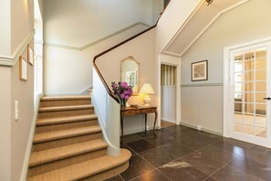 A staircase with a wooden handrail, a console table with a lamp, and a door with glass panels.