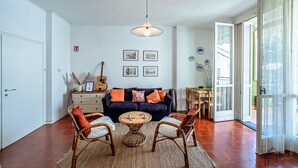 A living room with a sofa, chairs, a coffee table, a guitar, and framed pictures on the wall.