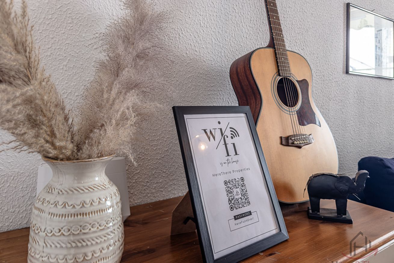 A framed WiFi sign, a guitar, and a decorative vase on a wooden surface.