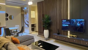 A modern living room with a sofa, coffee table, TV, and decorative elements. - Orange Green Apartment (Abuja)