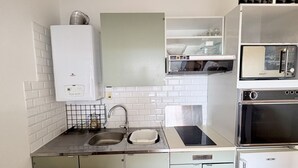 Et kompakt køkken med indbygget mikrobølgeovn, ovn og lille vask.