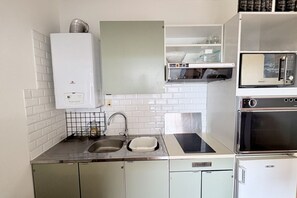 A compact kitchen with a built-in microwave, oven, and a small sink. - Getaway with an ocean view, balcony, and parking (Le Crotoy)