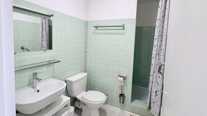 Et badeværelse med vask, toilet og bruseområde.