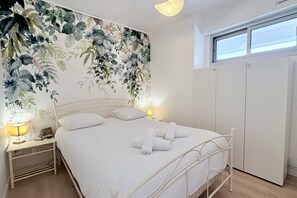 A bedroom with a bed, bedside lamps, a nightstand, a wardrobe, and a floral wallpaper. - Getaway with an ocean view, balcony, and parking (Le Crotoy)