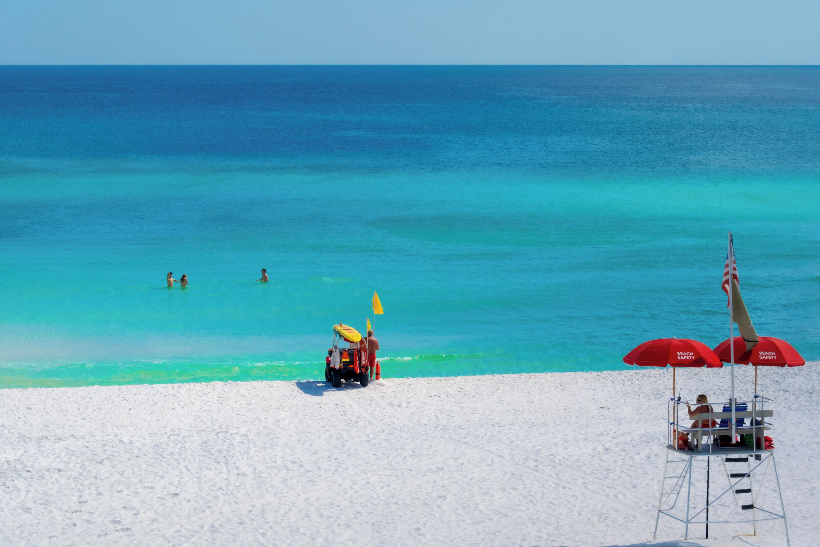 A beach with a lifeguard stand, a lifeguard chair, and a beach umbrella.