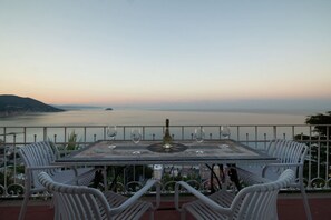 A table with four chairs, a bottle, and glasses, overlooking a body of water. - [Gulf Villa] Incredible View • Art • Relax (Laigueglia)