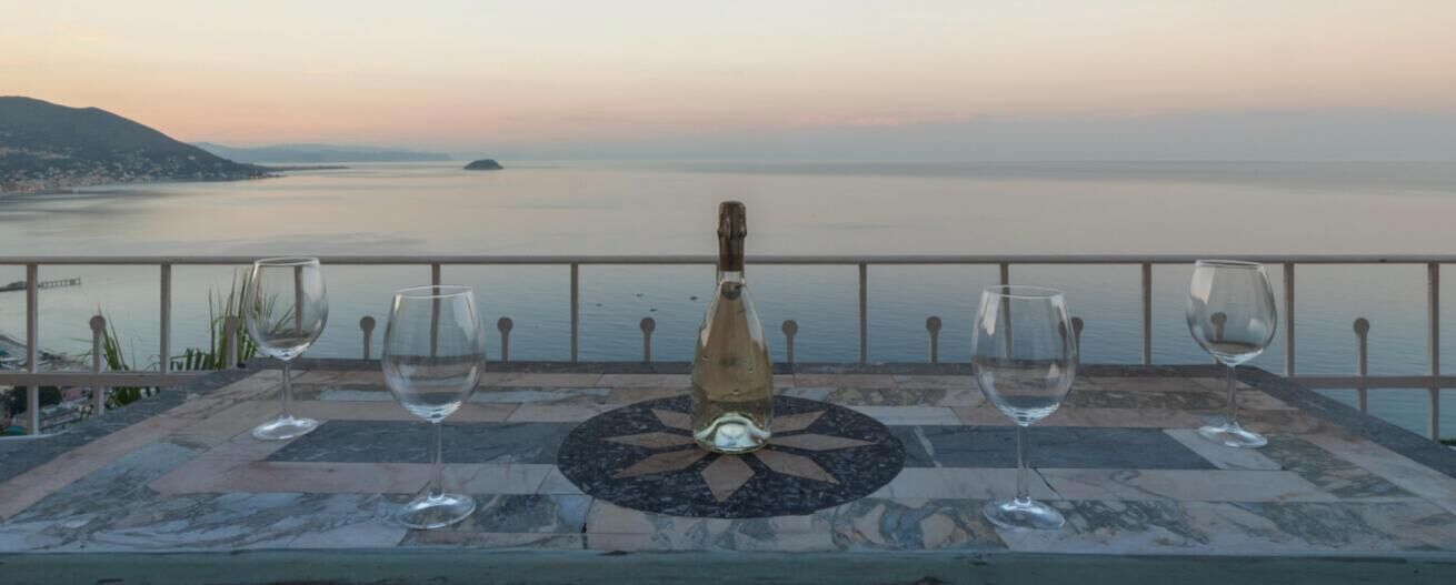 Um terraço com vista para o mar, uma garrafa e dois copos.