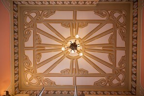 Eine Decke mit aufwendigen, symmetrischen Mustern und einem zentralen Chandelier.