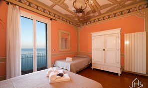 Ein Schlafzimmer mit Balkon, einem Bett mit Handtüchern, einem Kleiderschrank und einem Spiegel.