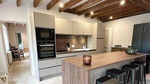 Eine moderne Küche mit einer zentralen Kochinsel, Barhocker und einem Essbereich im Hintergrund.