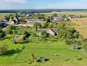 Un village rural avec des maisons, une piscine et de vastes champs.
