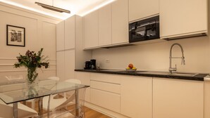 A modern kitchen with white cabinets, a glass dining table, and a stainless steel range hood. - A cozy and charming home featuring beautiful stone details, bright interiors, and a modern, relaxing atmosphere. Conveniently located in a central area, Atipico Apartment is perfect for guests who want to experience Florence with style and comfort.✔ Pe (Firenze)