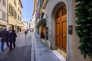 Eine schmale Gasse mit Häusern an beiden Seiten, einer Holztür mit einer Schild und ein Weihnachtsbaum auf der rechten Seite.