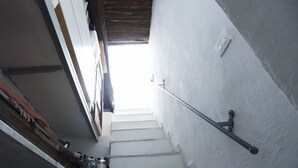 Uma escadaria com paredes brancas e corrimão de metal que leva a um andar superior.