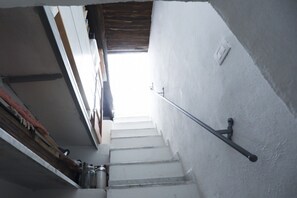 Eine Treppe mit weißen Wänden und einem Metallgeländer, das zu einer höheren Etage führt.