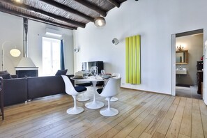 Ein modernes Wohnzimmer mit einer Couch, einem Esstisch mit Stühlen, einem Fernseher und einer leuchtend grünen Akzentwand.