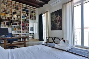 Ein Zimmer mit einem großen Bücherregal, einem Gemälde, einem Bett und einem Schreibtisch.