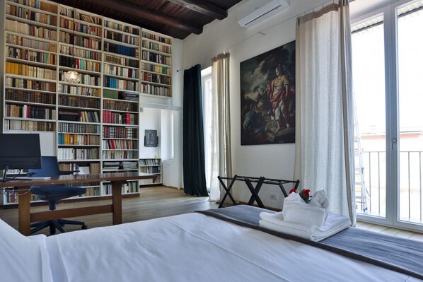Ein Zimmer mit einem großen Bücherregal, einem Gemälde, einem Bett und einem Schreibtisch.