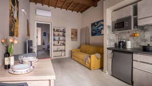A modern kitchen with a microwave, a small refrigerator, and a dining area with a table set for two. - Dimora Camaldoli - Authentic Florence Experience (Firenze)