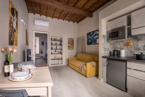 A modern kitchen with a microwave, a small refrigerator, and a dining area with a table set for two. - Dimora Camaldoli - Authentic Florence Experience (Firenze)