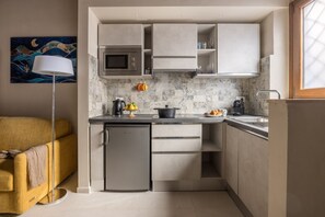 A compact kitchen with a microwave, a small refrigerator, and a sink. There is a painting on the wall and a floor lamp. - Dimora Camaldoli - Authentic Florence Experience (Firenze)