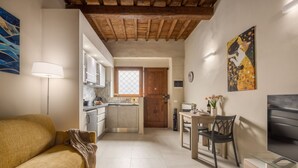 A modern kitchen with a wooden ceiling, a dining area with a table and chairs, and a sofa in a living area. - Dimora Camaldoli - Authentic Florence Experience (Firenze)