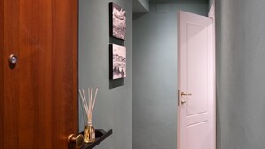 Un couloir avec une porte en bois, une porte blanche et deux photographies en noir et blanc accrochées au mur.