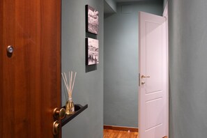 Ein Flur mit einer Holztür, einer weißen Tür und zwei schwarz-weißen Fotografien an der Wand.