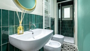 Une salle de bain avec un lavabo blanc, un miroir, des toilettes et un espace douche.