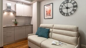 Une cuisine moderne avec un four encastré, une horloge suspendue et une affiche au mur.