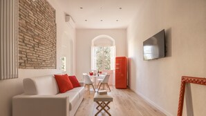 A modern living room with a white sofa, a dining table, and a red refrigerator. - Boboli Dreams- Luxury in the Historic Heart of Florence (Firenze)