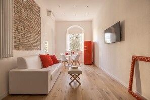 A modern living room with a white sofa, a dining table, and a red refrigerator. - Boboli Dreams- Luxury in the Historic Heart of Florence (Firenze)