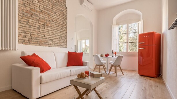 A modern living room with a white sofa, red cushions, a small table, and a red refrigerator. - Boboli Dreams- Luxury in the Historic Heart of Florence (Firenze)