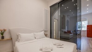 A modern bedroom with a large bed, a glass door leading to a living area, and a red cabinet. - Boboli Dreams- Luxury in the Historic Heart of Florence (Firenze)