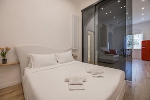 A modern bedroom with a large bed, a glass door leading to a living area, and a red cabinet. - Boboli Dreams- Luxury in the Historic Heart of Florence (Firenze)