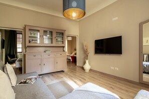 Ein Wohnzimmer mit einer Couch, einem Schrank, einem Flachbildfernseher und einer Vase mit Trockenpflanzen.